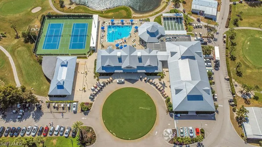 Expansive clubhouse facility featuring multiple buildings with gabled and hip roofs, a circular drive with a central lawn, and extensive parking areas
