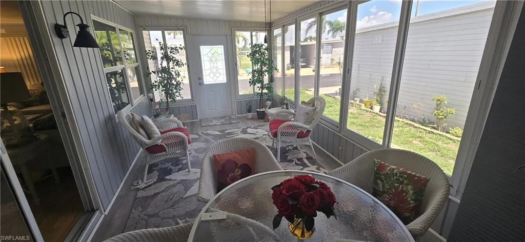 Enclosed patio featuring wall paneling, a patterned area rug, and multiple windows