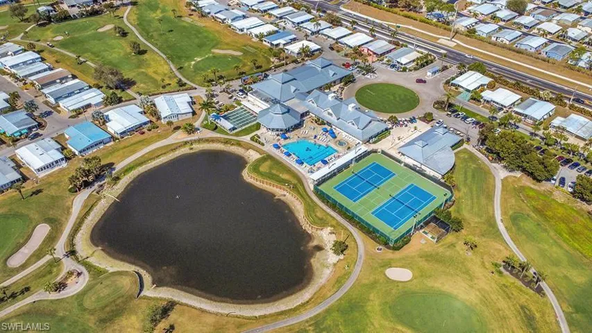 Aerial perspective highlighting a community hub with a central building, two tennis courts, and a swimming pool