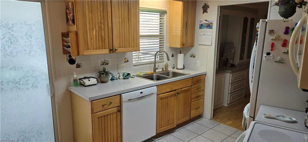Kitchen featuring wood-finish cabinetry, white countertops, and a double basin stainless steel sink