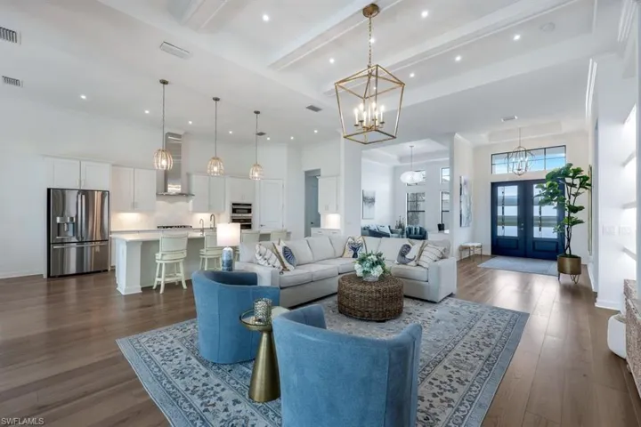 Living room featuring crown molding, french doors, dark wood-type flooring, beam ceiling, and a notable chandelier