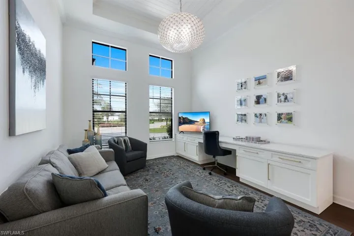 Home office featuring a towering ceiling, built in desk, a tray ceiling, crown molding, and dark hardwood / wood-style floors