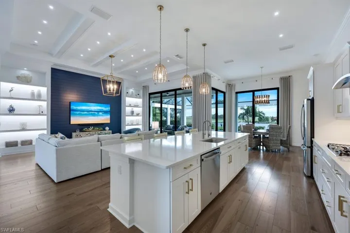 Kitchen featuring appliances with stainless steel finishes, white cabinets, sink, and an island with sink