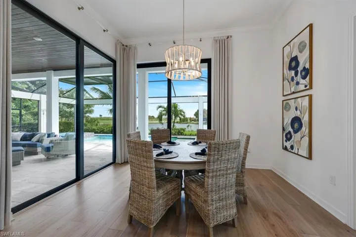 Dining area with a wealth of natural light, ornamental molding, hardwood / wood-style floors, and an inviting chandelier