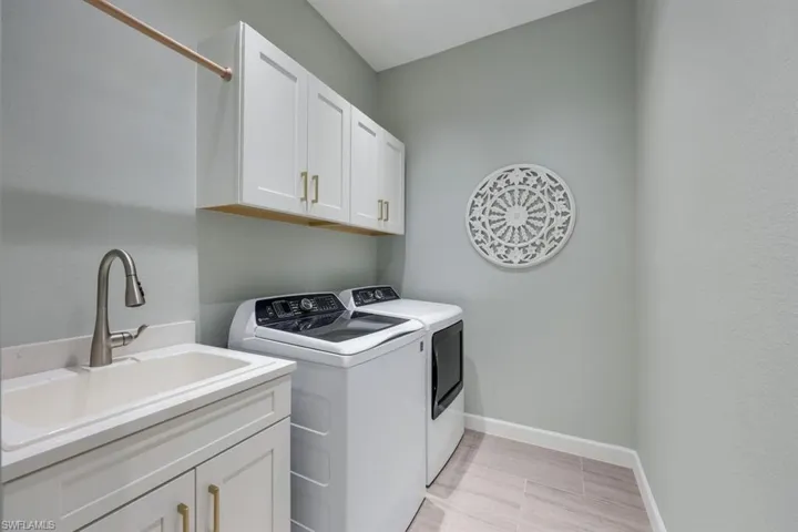 Clothes washing area with cabinets, sink, and separate washer and dryer