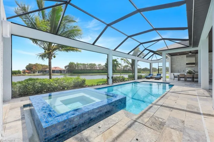 View of swimming pool featuring a water view, an in ground hot tub, a lanai, and a patio area