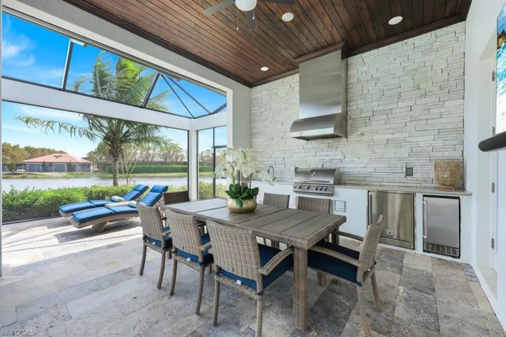 View of patio featuring an outdoor kitchen, ceiling fan, grilling area, a lanai, and a water view