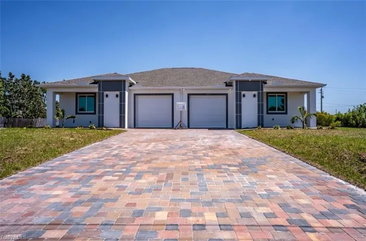 View of front of home featuring a front yard, decorative driveway, a garage, and stucco siding