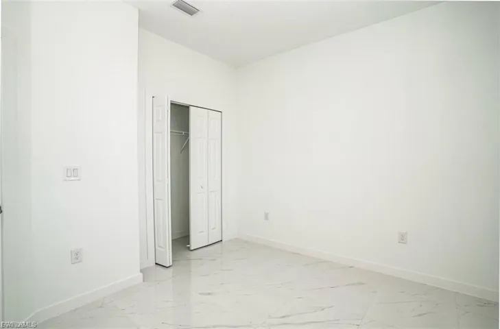 Unfurnished bedroom featuring light marble finish flooring and a closet