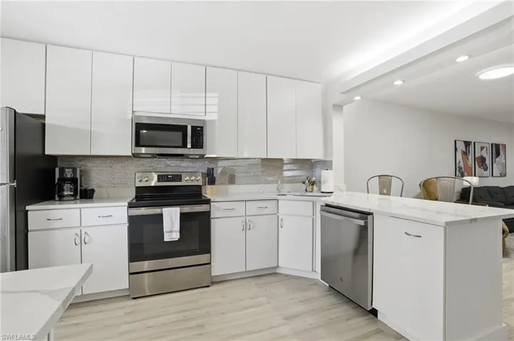 Kitchen featuring stainless steel appliances, light wood-style flooring, white cabinets, and recessed lighting
