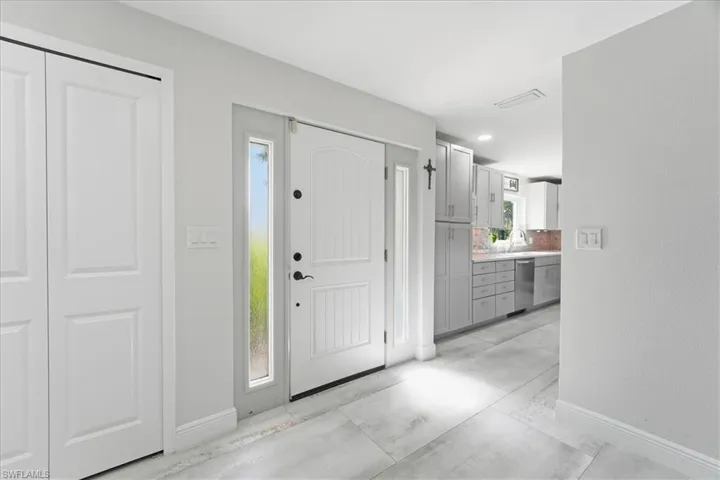 Entryway featuring a paneled door with a sidelight, light gray walls, and wood-finish flooring