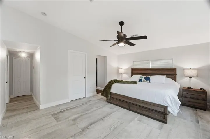 Spacious bedroom with wood-finish flooring, a contemporary ceiling fan, recessed lighting, and white baseboards