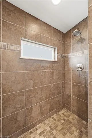Tiled shower enclosure featuring a rectangular transom window and a mosaic tile floor