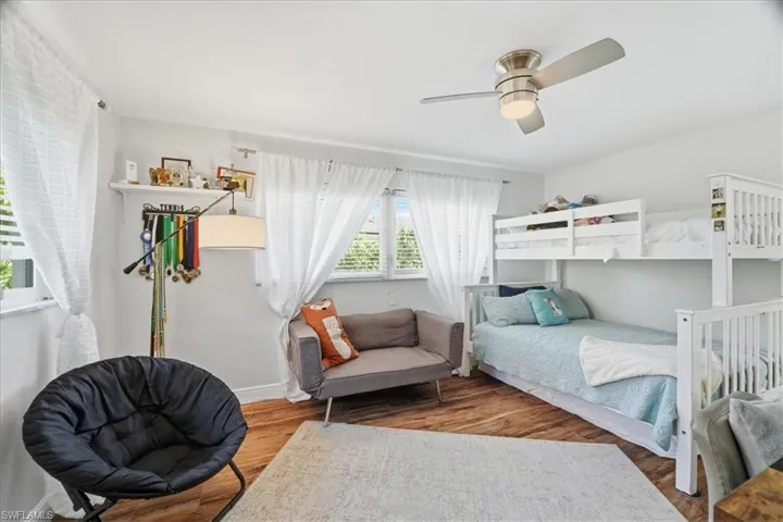 Room featuring wood-finish flooring, white walls, and a ceiling fan with integrated lighting