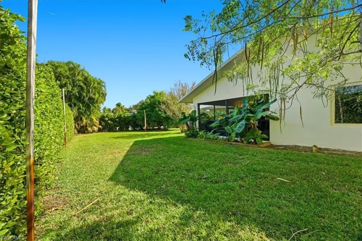 Expansive green lawn with established landscaping, featuring a white exterior and a screened patio