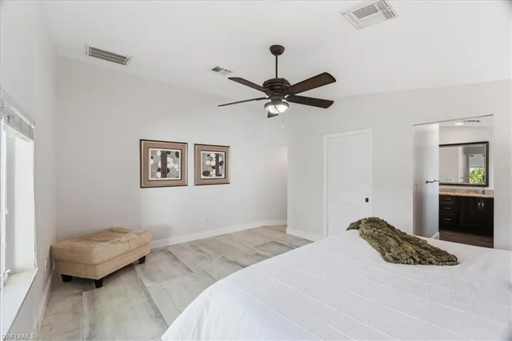 Spacious room featuring vaulted ceilings, a ceiling fan with integrated lighting, and light-toned wood-finish flooring
