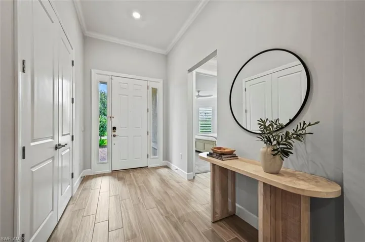 Foyer entrance with wood finish floors and ornamental molding