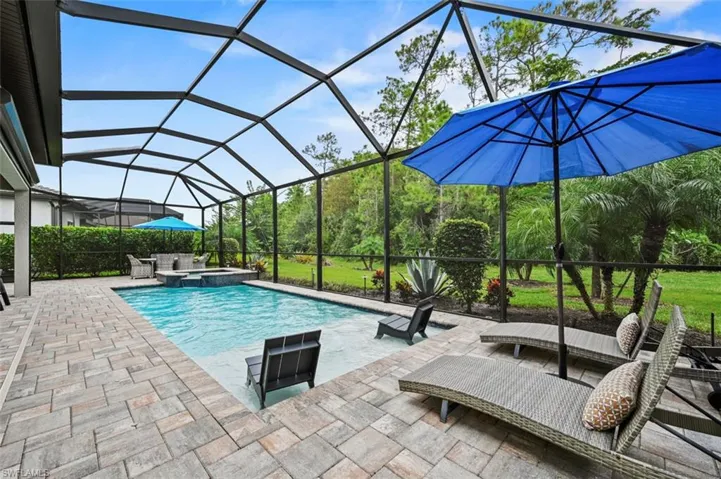 View of swimming pool featuring a sunroom, a pool with connected hot tub, a patio, and glass enclosure