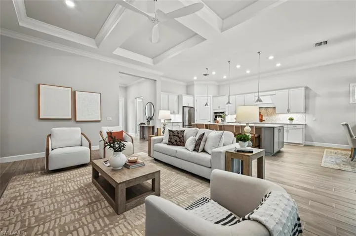 Living room featuring coffered ceiling, a ceiling fan, crown molding, light wood-style floors, and beamed ceiling