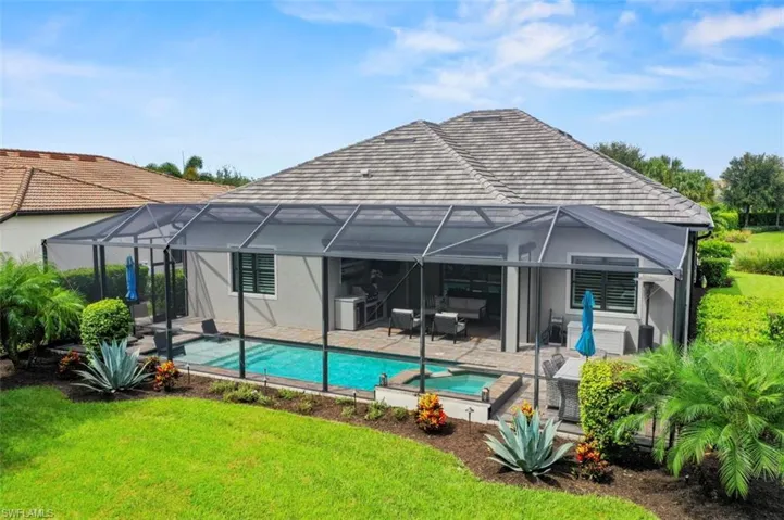 Rear view of property with a sunroom, a patio area, a pool with connected hot tub, glass enclosure, and a yard