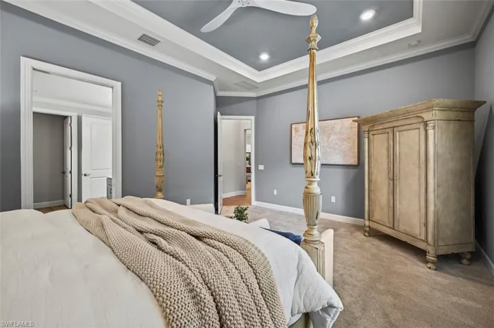 Carpeted bedroom with ornamental molding, ceiling fan, a raised ceiling, and recessed lighting