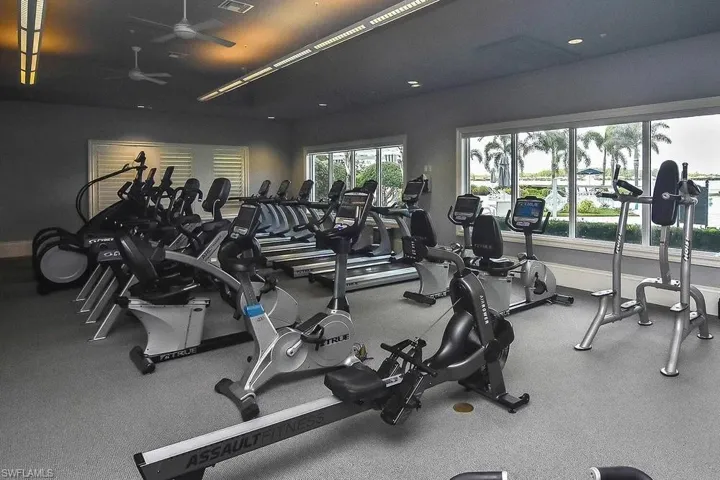 Gym with ceiling fan and baseboards