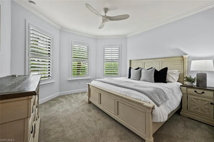 Bedroom with ornamental molding, dark colored carpet, and a ceiling fan