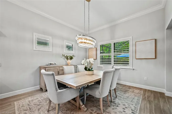 Dining area featuring wood tiled floors, crown molding, and a chandelier