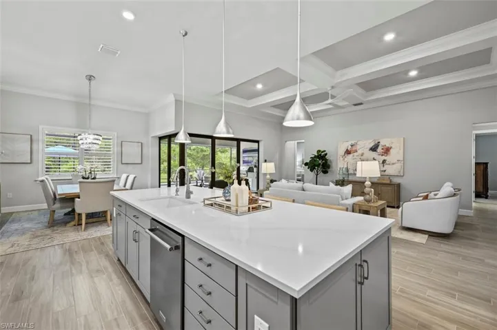Kitchen with gray cabinetry, pendant lighting, ornamental molding, a center island with sink, and recessed lighting