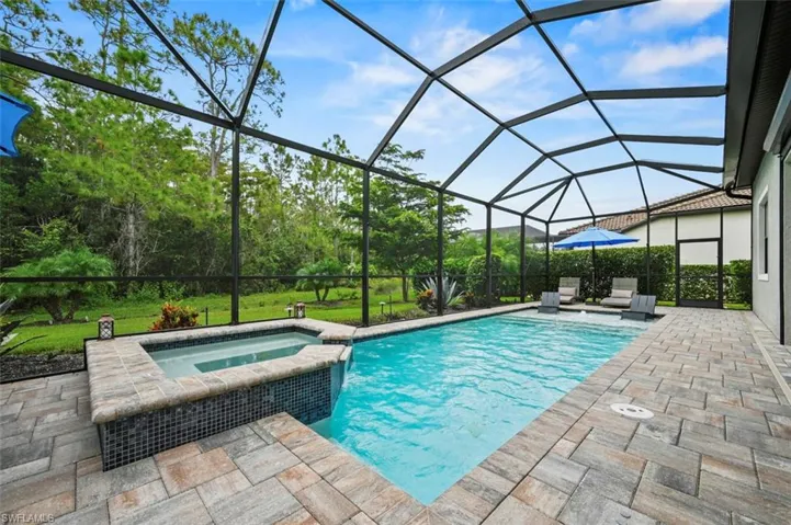 View of pool featuring a sunroom, glass enclosure, a pool with connected hot tub, and a patio