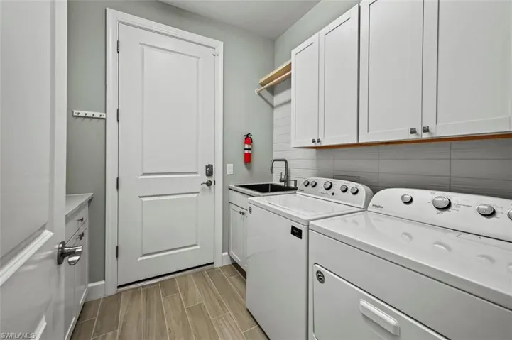 Laundry room with wood finish floors, cabinet space, and washing machine and clothes dryer