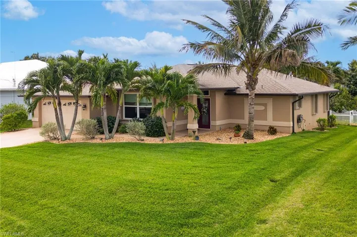 Ranch-style home featuring a garage, driveway, stucco siding, and a front yard