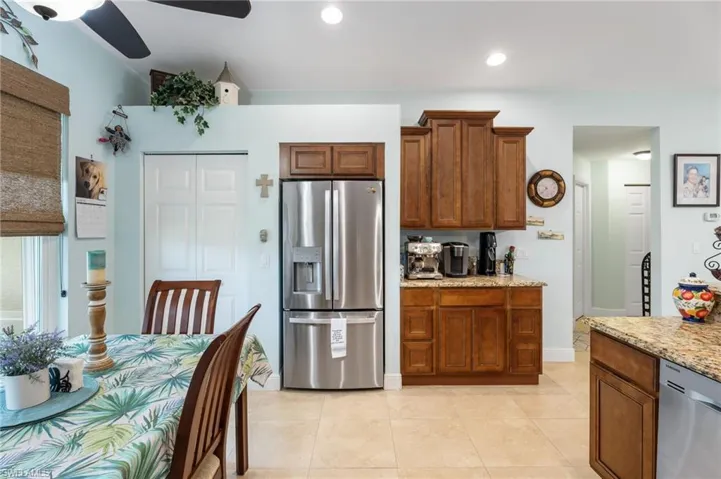 Kitchen featuring wood finish cabinetry, stainless steel appliances, a ceiling fan, light stone countertops, and recessed lighting