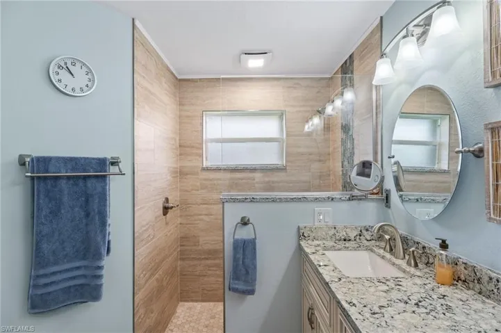 Full bath with vanity, a walk in shower, and plenty of natural light