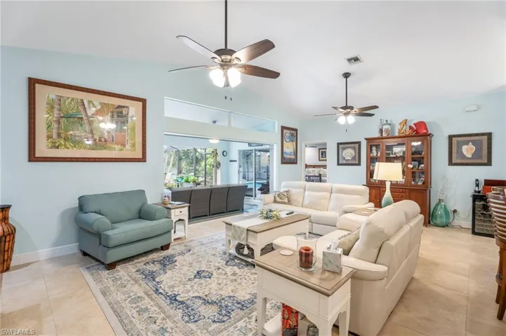 Living area featuring vaulted ceiling, ceiling fan, and light tile patterned floors