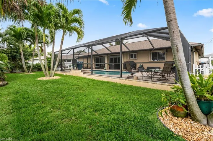 Rear view of house featuring a sunroom, a lanai, an outdoor pool, a patio, and a yard
