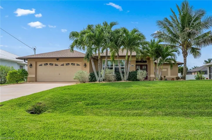 View of front of house with an attached garage, driveway, stucco siding, and a front lawn