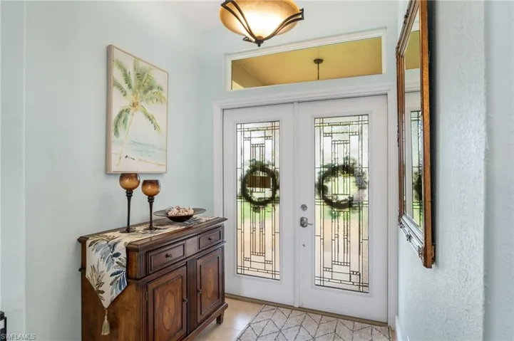 Foyer featuring french doors, light tile patterned floors, and a textured wall