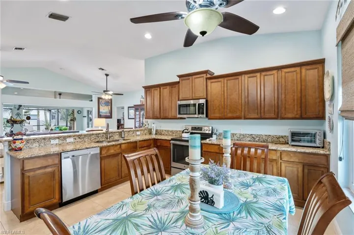 Kitchen with wood finish cabinetry, stainless steel appliances, light stone counters, a peninsula, and recessed lighting
