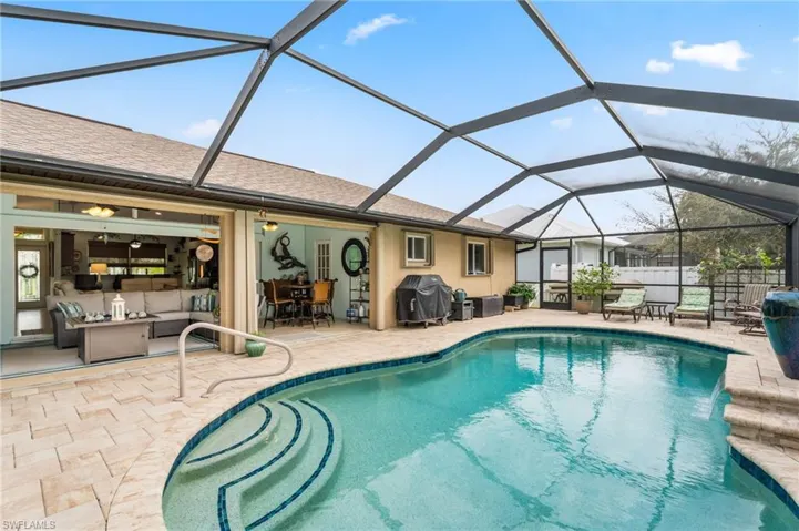 View of swimming pool with a sunroom, a grill, outdoor dining area, patio surround, and glass enclosure