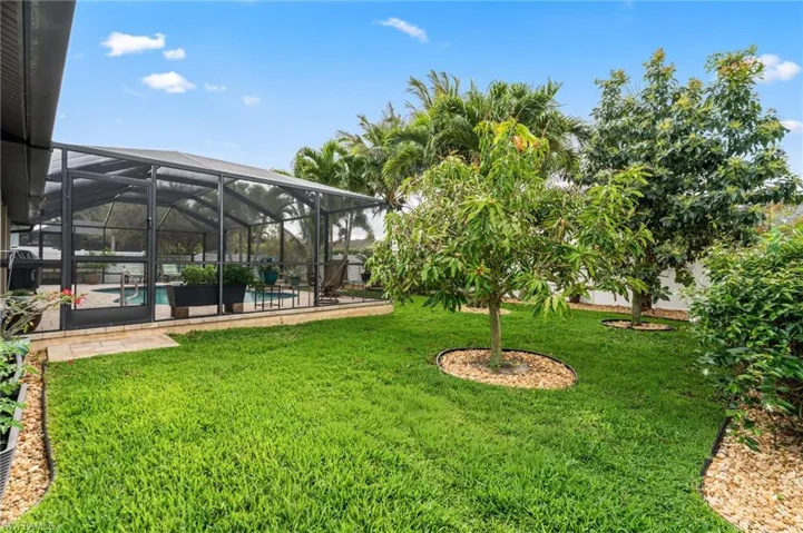 View of grassy yard with an outdoor pool, glass enclosure, a sunroom, and a patio area