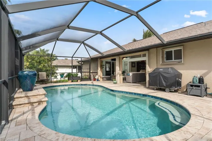 Swimming pool featuring a patio area, a sunroom, grilling area, and glass enclosure