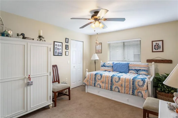 Bedroom with light carpet, a ceiling fan, and a closet