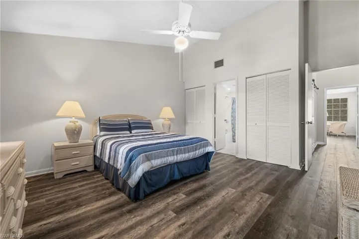 Bedroom featuring two closets, wood finished floors, high vaulted ceiling, and a ceiling fan