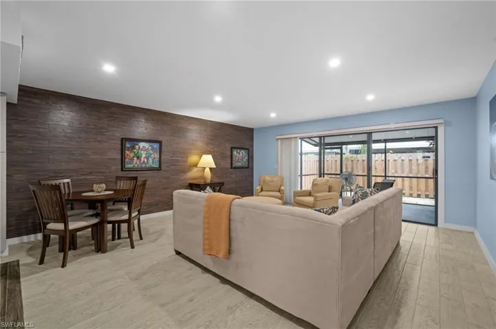 Living area with an accent wall, recessed lighting, light wood-style flooring, and wood walls