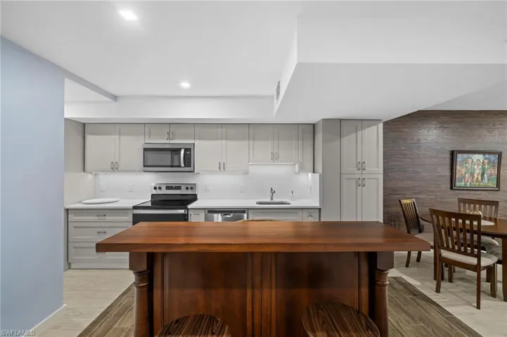 Kitchen with appliances with stainless steel finishes, butcher block counters, light wood-style floors, wooden walls, and recessed lighting