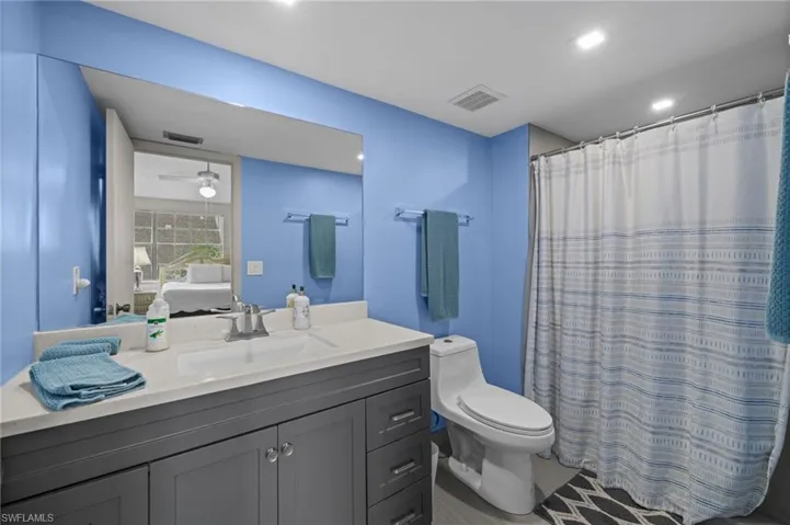 Ensuite bathroom featuring vanity, a shower with curtain, and a ceiling fan