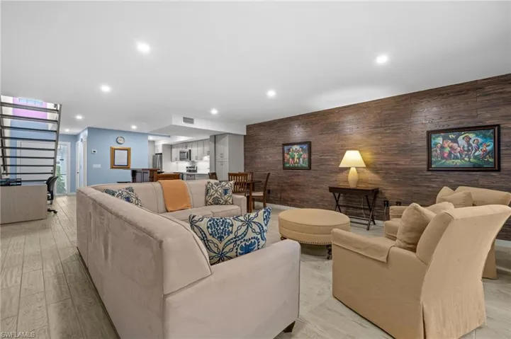 Living area with wood walls, recessed lighting, an accent wall, and light wood-style flooring