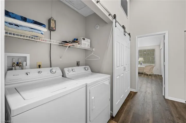 Washroom featuring a barn door, dark wood finished floors, and independent washer and dryer