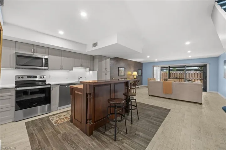 Kitchen with appliances with stainless steel finishes, gray cabinetry, light wood-type flooring, a center island, and recessed lighting
